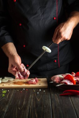 Aşçı şişte çiğ et yiyor. Mutfakta bir şefin elleriyle şiş kebap pişirme işlemi.