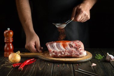Şef taze et kaburgalarına kırmızı biber serpiyor. Lezzetli sokak yemeği ya da ızgara yapma fikri. Reklam için alanı olan siyah arkaplan