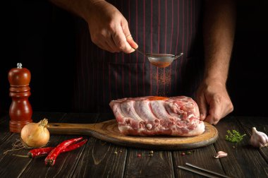 Şef taze et kaburgalarına kırmızı biber serpiyor. Lezzetli sokak yemeği ya da ızgara yapma fikri. Reklamcılık için alanı olan koyu arkaplan