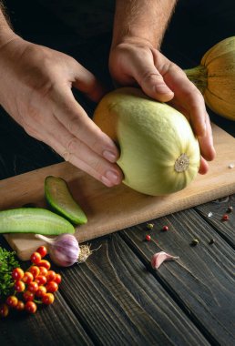 Aşçı mutfak masasında taze kabak hazırlar. Şefin ellerine yakın çekim. Aşçılıkta, kabağın kalın eti kullanılır.