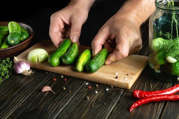 stock image The cook hands sort cucumbers before canning in a jar. Work environment on kitchen table with vegetables and spices