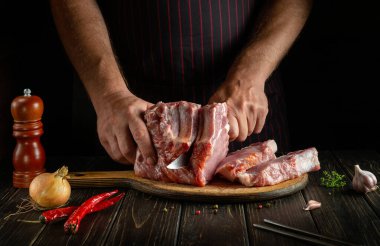 Aşçı ızgaradan önce bir kesme tahtasıyla çiğ kaburga keser. Otel ya da restoran için et yemeği fikri. Dana pirzolası nefis bir öğle yemeği.