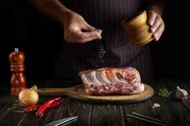 Profesyonel şef çiğ kaburga ve tuz serpiyor. Otel veya restoran için lezzetli yemekler pişirme kavramı.