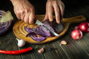 Vejetaryen yemeği hazırlamak için mutfak tahtasındaki bir aşçının elleriyle kırmızı lahana dilimlemek..