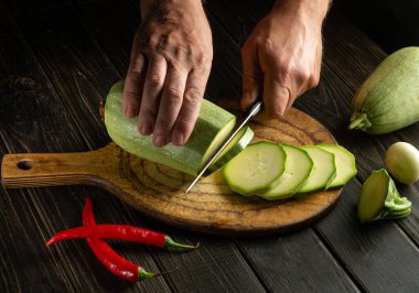 Şef tahta bir kesme tahtasının üzerinde bir bıçakla taze kabak keser. Kabağın kalın eti İngiliz yemeklerinde kullanılır.
