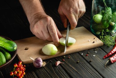 Aşçı kavanozda baharat ve salatalıkla turşu ya da turşu yapmak için taze soğan keser. Mutfak masasında çalışırken aşçı ellerinin yakın çekimi.