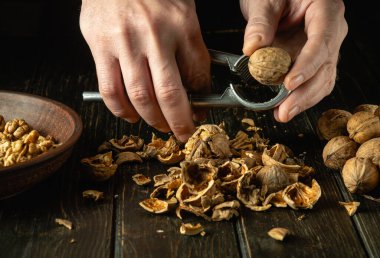 Bir şefin elinde fındık kıracağıyla fındık soymak. Tabakta ve mutfak masasında soyulmuş ceviz.