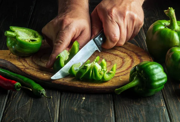 Experienced chef cuts green peppers on a cutting board for cooking lecho. Peasant delicious food. Copy Space