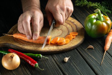 Şef vejetaryen yemek hazırlamak için havuç keser. Lezzetli köylü ürünleri. Boşluğu kopyala