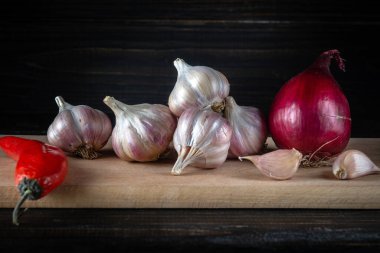 Sarımsak, karanfil ve soğan, yemeğe eklenmeden önce siyah bir antika masanın üzerinde. Uzayı kopyala Baharatlı Asya yemeği yapma fikri sarımsak ve biberli.
