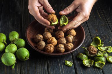Yeşil kabuktan fındık soyan birinin yakın çekimi. Mutfak masasında çalışma ortamı