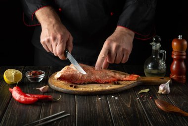 Aşçı taze Sebastes balığı hazırlar. Balık yemi pişirmeye hazırlanıyorum. Aşçı bıçakla kesiyor Kızartmadan önce kırmızı balığı