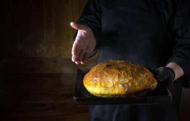 Fırıncının elinde taze pişmiş buğday ekmeği sunumu. Reklam için yer var. Evde ekmek pişirme kavramı..