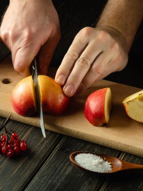 Lezzetli meyve suyu yapmak için tahta kesme tahtasına elma kesen bir şef elin yakın çekimi. Elma diyeti fikri. Boşluğu kopyala.