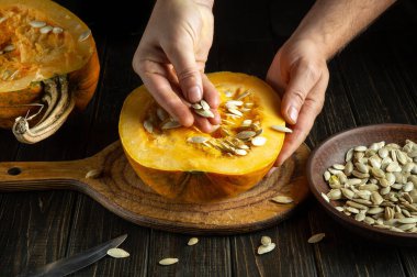 Aşçı yemek pişirirken kullanılan kokulu sebze yağını hazırlamadan önce kabak çekirdeklerini çıkarır. Mutfak masasında çalışma ortamı