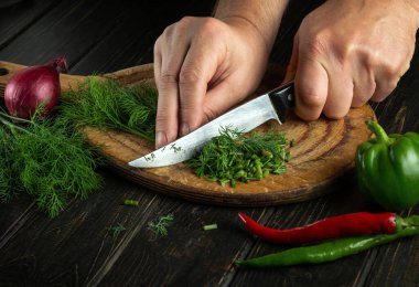 Bıçaklı bir aşçının elleri kesme tahtasına yeşil dereotu ya da rezene keser. Vejetaryen menüsü veya restoran veya otel tarifi