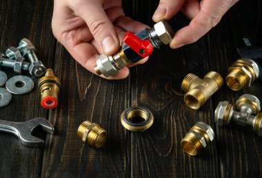 Usta tesisatçı teçhizatı tamir ederken ya da benzin yerleştirirken pirinç tesisatlarını birbirine bağlar. Atölyede çalışırken ustabaşının ellerini kapat..