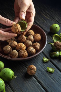 Aşçının elleri yeşil kabuktaki cevizleri temizler. Mutfak masasında çalışma ortamı. Boşluğu kopyala