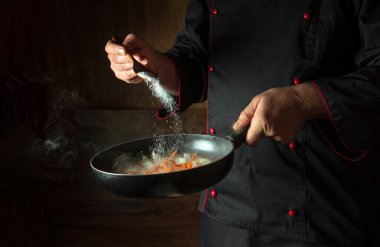 Şef sıcak tavaya tuz ekler. Akşam yemeği pişirmeden önce havuçla soğan kızartıyorum. Tarif için ya da arka planda menü için yer var. Avrupa mutfağı