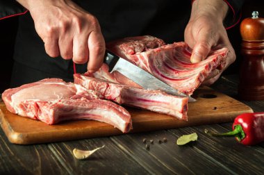 Chef cutting raw beef ribs with a sharp knife on wooden board. Process of cooking grilled bbq ribs. Asian cuisine