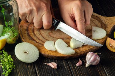 Preservation of vegetables in a jar. The chef cuts a ripe onion on a cutting board. Peasant food. Recipe for restaurant and hotel.