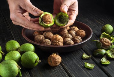 Chef's hands clean the walnuts on the kitchen table for use in cooking. Close-up of a cook hands with a walnut