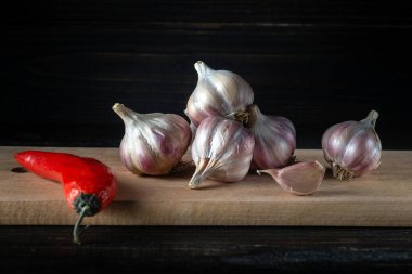 Garlic cloves on a wooden cutting board. Fresh peeled garlic and red pepper. Copy space.