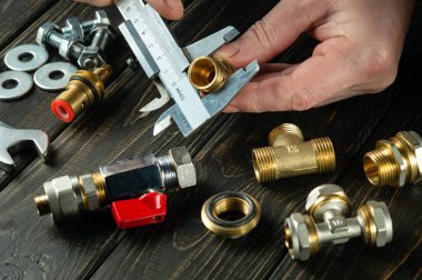 Measuring the diameter of a fitting with a caliper in the hands of a master plumber. Installation or repair of gas equipment.