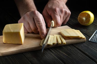 Aşçının eli bıçakla peyniri tadımlık küçük parçalara ayırdı. Lezzetli Süt Peyniri Tarifi Sunumu. Boşluğu kopyala