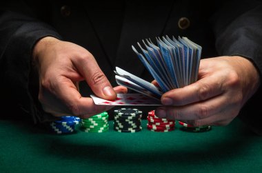 Profesyonel bir satıcı ya da krupiye, yeşil bir masada elinde fiş olan bir kulüpte iskambil kağıtlarını çabucak karıştırır. Kumarhanede başarılı bir poker oyunu konsepti.