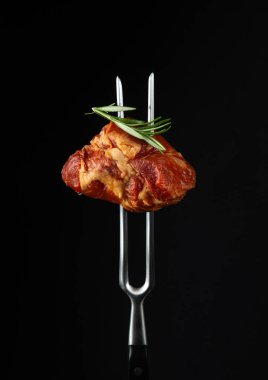 Smoked steak or ham with rosemary on a fork. Natural product from an organic farm. Menu for hotel on black background
