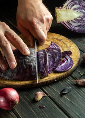 Aşçının elleri bıçakla kırmızı lahana kesti. Restoranın mutfağında sebze salatası pişiriyorum. Sebze diyeti fikri