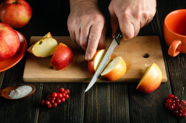 Aşçının eline bıçakla yakın plan kesilmiş elmalar komposto ya da meyve suyu yapmak için. Bir dizi vitamin için elma diyeti