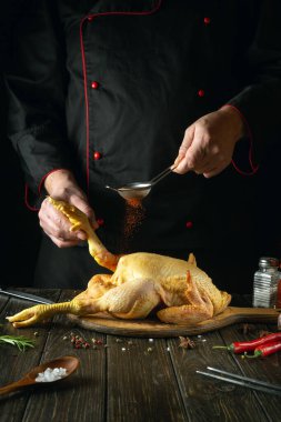 The chef prepares raw chicken in the kitchen. The cook adds paprika to the rooster before frying. Preparing to fry fried chicken.