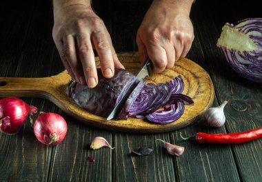 Aşçının elleri kesme tahtasındaki kırmızı lahana bıçağıyla kesilmiş. Mutfakta sebze salatası pişiriyorum. Köylü ürünlerinden sebze diyeti fikri