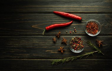 Siyah bir masada çeşitli baharatlar ve biberler. Cam bardaklardaki baharatlar. Yukarıdan bak. Tarif için karanlık boşluk.