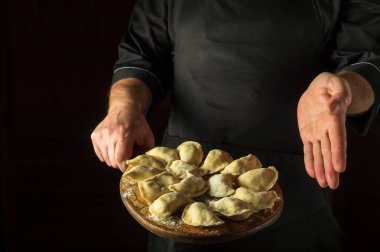 Lokantanın mutfağında şefin elleriyle hamur köftesi pişirmek. Kesme tahtasında hamur tatlısı sunumu. Lezzetli bir kahvaltı ya da yemek tarifi ya da menüsü olan bir yer..