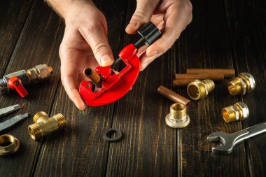 Usta bir tesisatçı boru kesiciyle bakır boruyu kesmeye çalışıyor. Atölyeye gaz teçhizatı kurulumu veya onarımı.