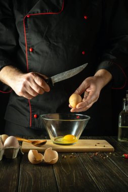 Şef lezzetli bir kahvaltı hazırlamak için yumurta kırmaya çalışıyor. Mutfakta çalışma ortamı. Restoran ya da otel için menü fikri.