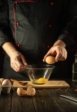 Şefin elinden çıkan yumurtalardan kahvaltıda lezzetli bir omlet pişirmek. Mutfak masasında çalışma ortamı. Yumurta ellerde..