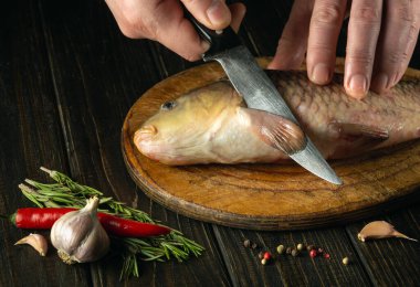 Sazanı temizlemeden önce mutfak masasında bıçakla şefin ellerini yakın plan çek. Mutfak masasında baharat ve biberle balık tabağı pişirmek..