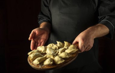 Şef mutfakta hamur tatlısı hazırlar. Eline çiğ hamur köftesi ile tahta kesmek. Boşluğu kopyala.