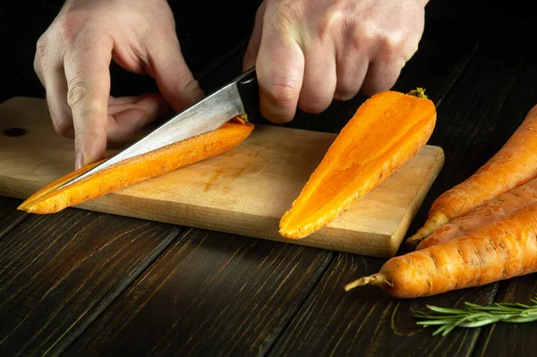 包丁で調理する料理人の手は 野菜とベジタリアン料理を準備する前に キッチンカットボード上の新鮮な生ニンジンをカット — ストック写真