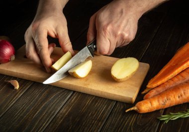 Şef çiğ patatesleri bıçakla küçük parçalara ayırır. Mutfakta çalışırken aşçıya yakın çekim. Lezzetli bir kahvaltı ya da akşam yemeği