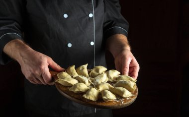 Aşçı elinde çiğ hamur köfteleriyle bir mutfak tahtası tutuyor. Lezzetli bir kahvaltı ya da yemek tarifi ya da menüsü olan bir yer.