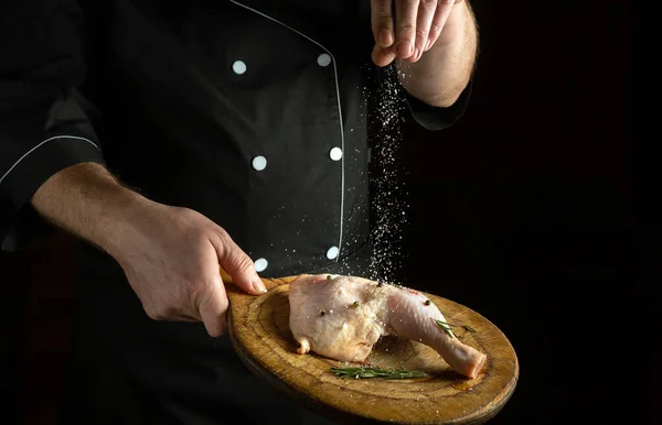 The chef throws salt on the leg of the chicken. The idea of cooking delicious food for the hotel. Copy space