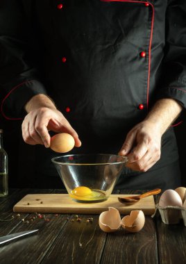Şefin elinde yumurta. Pişirdiği yumurtalardan kahvaltıda nefis bir omlet pişiriyor. Mutfak masasında çalışma ortamı