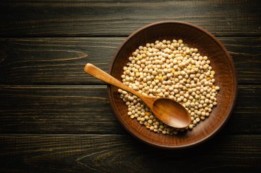 Pişirmeden önce bir tabak dolusu kuru bezelye ve eskimiş karanlık bir masada bir kaşık. Restoran ya da otel için tarif ya da menü alanı.