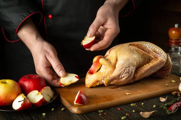 The cook adds apples to raw duck before roasting in the oven. Cooking a national dish or Peking duck in the restaurant kitchen by the hands of a chef