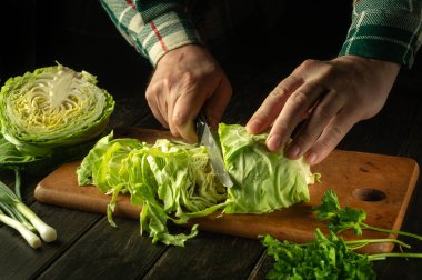Aşçının elleri, ulusal ya da vejetaryen yemekleri hazırlamadan önce mutfak tahtasındaki bıçakla taze lahana kesiyor. Köylü mutfağı..